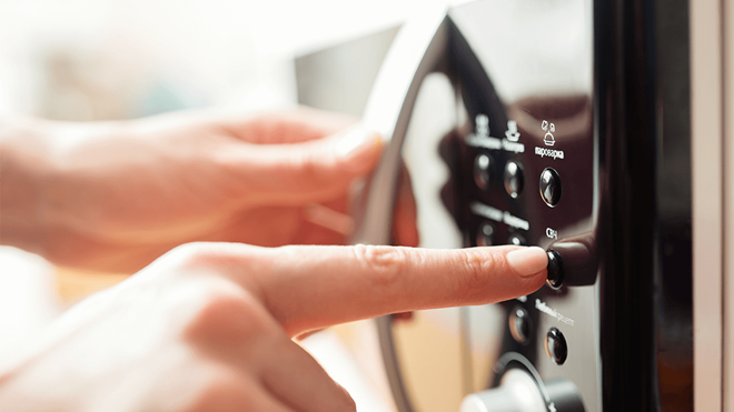 closeup of a person using the controls on a microwave